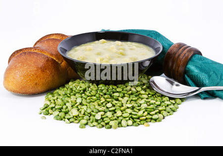 Split pea soup en noir bol avec du pain frais, vert et brun bois ronds de serviette sur pois ingrédient. Banque D'Images