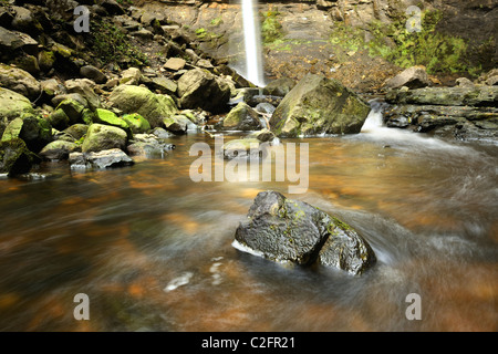 L'eau qui coulait à travers les rochers au pied de Hardraw Force, la plus haute cascade de l'Angleterre, près de Hawes, Yorkshire du Nord. Banque D'Images