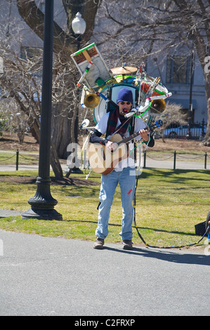 Un homme effectue dans Boston Public Garden avec une guitare et de nombreux instruments fixé à son retour Banque D'Images