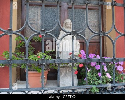 Une statue de la Vierge Marie se trouve derrière les barreaux d'une fenêtre côté rue d'une résidence à Antigua, Guatemala. Banque D'Images