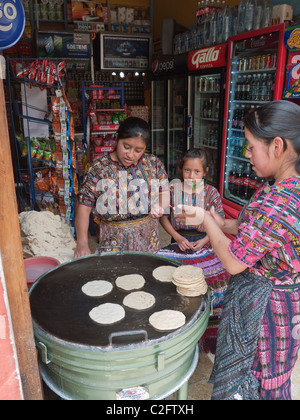 Femme deux tortillas cook en vente sur une grill juste à l'intérieur d'un petit magasin sur la rue dans le centre de Antigua, une jeune fille les regarde. Banque D'Images