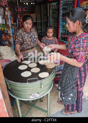 Femme deux tortillas cook en vente sur une grill juste à l'intérieur d'un petit magasin sur la rue dans le centre de Antigua, une jeune fille les regarde. Banque D'Images