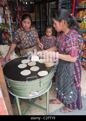 Femme deux tortillas cook en vente sur une grill juste à l'intérieur d'un petit magasin sur la rue dans le centre de Antigua, une jeune fille les regarde. Banque D'Images