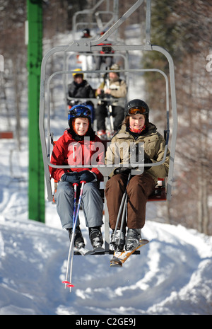 Deux garçons sur un télésiège au centre de ski de Vogel sur la la Sija - Zadnji Vogel piste dans le parc national du Triglav de Slovénie Banque D'Images