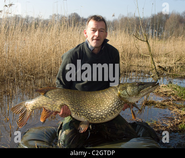 Portrait of fisherman holding grande femelle brochet capturé à Wykeham Lakes, North Yorkshire, UK Banque D'Images