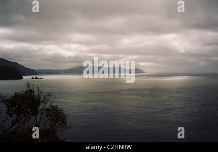 Vue depuis le cap Huay sur la péninsule de Tasman avec éclatement de la lumière du soleil à travers les nuages et illuminant l'océan. Banque D'Images