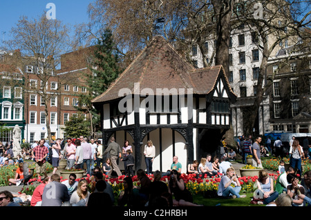 Les touristes et les employés de bureau se réunissent à Soho Square, Londres pour profiter d'une journée de printemps chaude à l'heure du déjeuner. Banque D'Images