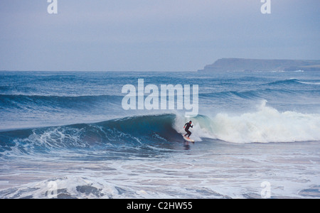 Surfer une vague à East Strand, Portrush, comté d'Antrim, en Irlande du Nord. Banque D'Images