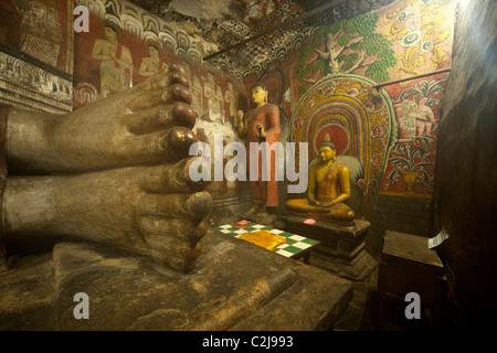 Pied géant d'un bouddha couché et plus les statues de Bouddha à l'intérieur du complexe du Temple Dambulla au Sri Lanka Banque D'Images