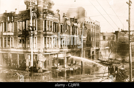 Bloc de bâtiments brûlés à San Francisco après le tremblement de terre de 1906 avec un camion à incendie pulvériser de l'eau sur eux Banque D'Images