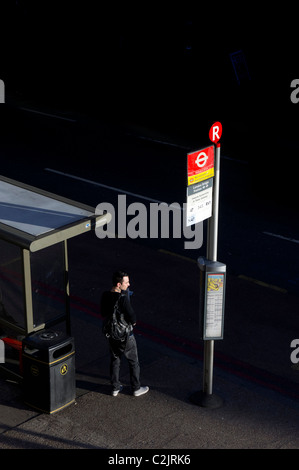 L'homme en attente d'autobus à l'arrêt de bus la Station London Bridge, London, England, UK Banque D'Images