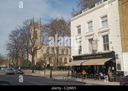 Le Sydney Arms public house avec l'église paroissiale de St Luc, derrière Chelsea. Sydney Street, SW3, Chelsea, London, UK. Banque D'Images