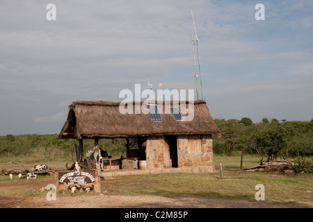 Panneaux PV solaire et éolienne sur toit de chaume, d'entrée de la réserve Masai Mara Kenya Banque D'Images