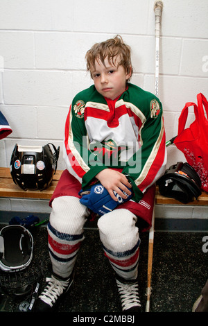 Garçon de 8 ans dans la salle de casier portant des uniformes de hockey fatigué après un match. St Paul Minnesota MN USA Banque D'Images