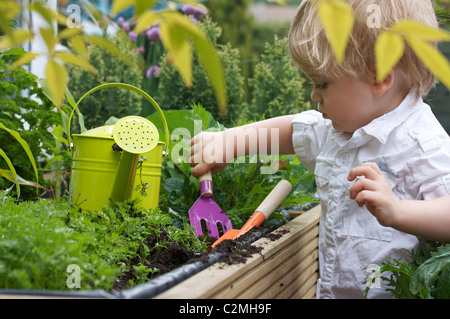 Un enfant en extérieur avec des outils de jardinage bébé Banque D'Images