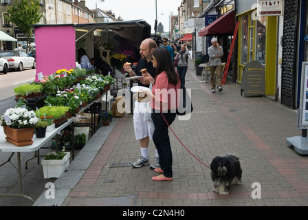 Northcote Road, Clapham, London Borough of Wandsworth. SW11 couple avec chien d'animal de compagnie manger dans la rue en pensant à l'achat de quelques plantes. HOMER SYKES, ROYAUME-UNI Banque D'Images