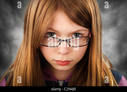 Jeune fille (9) à la plus grave haut de ses lunettes, avec moody background Banque D'Images