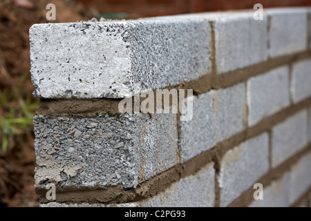 Mur de maçonnerie nouvellement posées avec la moitié en parpaings de ciment construction d'un mur de soutènement en bloc au Royaume-Uni Banque D'Images