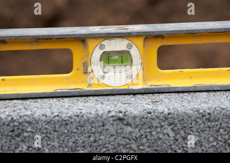 En utilisant un niveau à bulle pour vérifier les niveaux lors de la construction d'un mur de soutènement en bloc au Royaume-Uni Banque D'Images