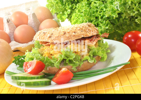 Le seigle bagel avec salade, œufs brouillés et bacon Banque D'Images