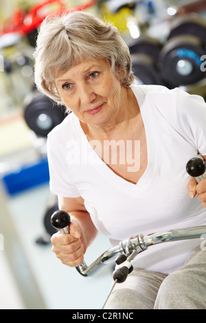 Photo de femme active les muscles de pompage sur l'équipement spécial Banque D'Images