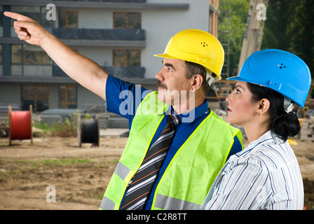 Deux architectes homme mûr et jeune femme travaillant sur place,l'homme pointant à quelque part et ils ont une discussion Banque D'Images