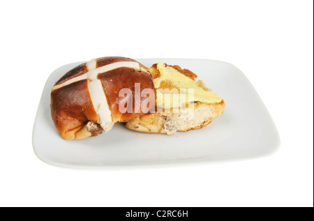 Hot cross bun beurré sur une plaque isolés contre white Banque D'Images