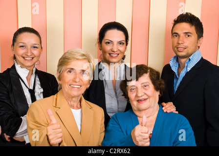 Groupe réussi de cinq personnes avec des personnes âgées en face giving Thumbs up Banque D'Images