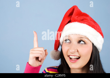 Girl with Santa hat pointe vers le haut pour copier l'espace et à la très surpris et heureux Banque D'Images