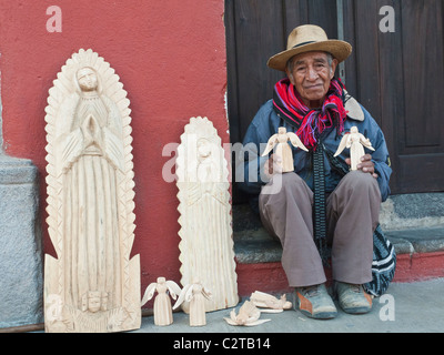 Un sculpteur sur bois qui vend ses produits artisanaux aux touristes dans la ville coloniale d'Antigua, Guatemala. Banque D'Images
