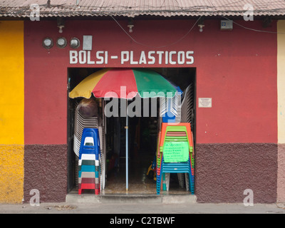 La terre cuite et peint marron store front avec des chaises en plastique et des parasols patio à vendre dans la ville coloniale espagnole o Banque D'Images