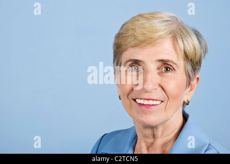 Portrait of smiling senior business woman sur fond bleu,copie espace pour message texte dans la partie gauche de l'image Banque D'Images