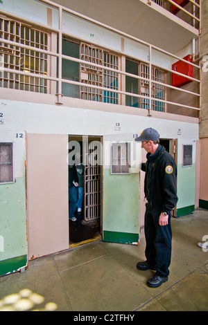 Un bénévole en uniforme ouvre la porte d'une cellule d'isolement pour les touristes en bloc D à l'ancienne prison d'Alcatraz. Banque D'Images