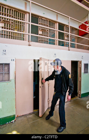Un bénévole en uniforme ouvre la porte d'une cellule d'isolement pour les touristes en bloc D à l'ancienne prison d'Alcatraz. Banque D'Images