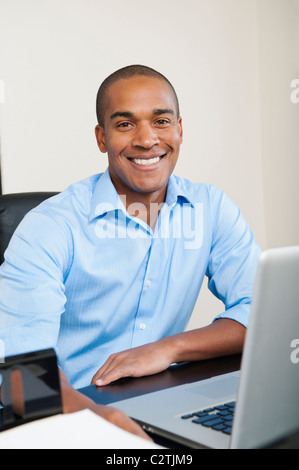 Smiling African American businessman sitting at desk Banque D'Images