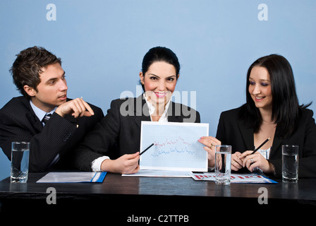 Les gens assis dans une ligne à la table et avoir une réunion ,ils montrant un tableau financier et l'ensemble du débat Banque D'Images