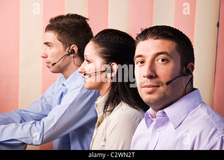 Les opérateurs du centre d'appel avec casque ,deux hommes et une femme en travail social,selective focus on last man Banque D'Images