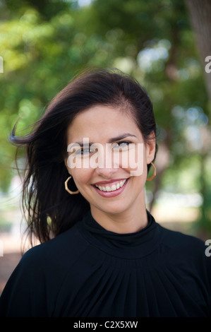La beauté brune en souriant. Belle femme 30s outdoors smiling à l'ombre d'un arbre, vêtu de noir haut. Banque D'Images