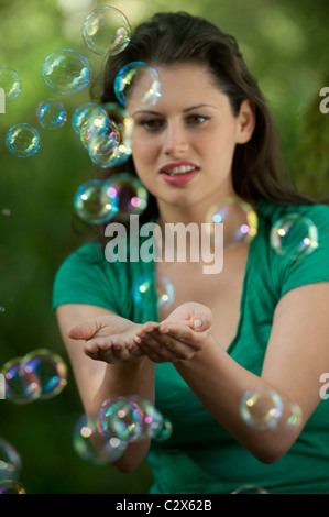 Caucasian woman tente de prendre des bulles dans ses mains Banque D'Images
