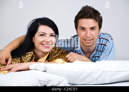 Portrait of happy couple lying on bed, man hugging woman et les deux smiling Banque D'Images