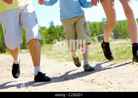 Les jambes de trois membres de la famille de descendre le chemin forestier pendant les vacances d'été Banque D'Images