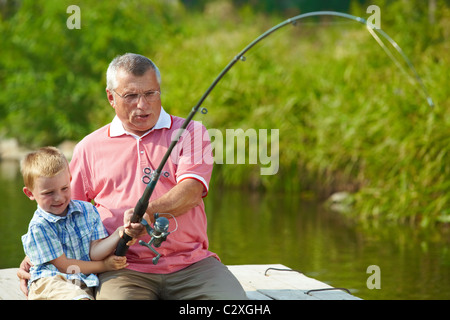 Photo de grand-père et petit-fils de pêche ensemble tout en tige de traction Banque D'Images