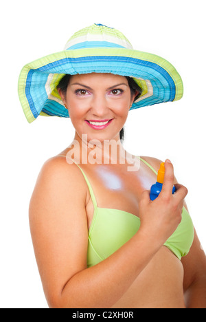 Très belle femme avec chapeau maillot et l'application de crème solaire sur la poitrine et smiling isolé sur fond blanc Banque D'Images