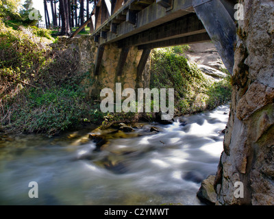 Vieux pont de bois sur une rivière d'eaux soyeux Banque D'Images