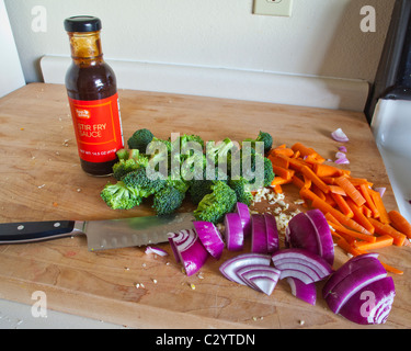 Couper les légumes prêts à être sautés, avec une bouteille de sauce sauté Banque D'Images