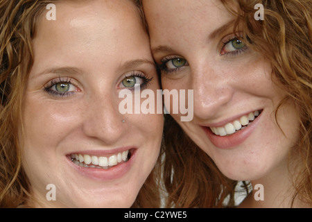 Closeup Portrait of Twin Sisters Posing joue contre joue et souriant Banque D'Images