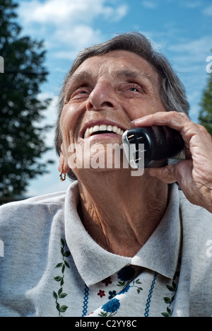 Un heureux, senior couple bénéficie d'une conversation sur un téléphone sans fil, téléphone mobile. Banque D'Images