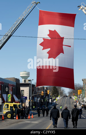 Un drapeau canadien est suspendu par deux camions de pompiers de l'échelle pendant la procession funéraire public pour Ken Rae et Ray Walter. Banque D'Images