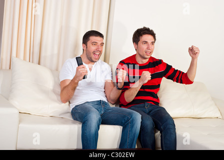 Deux hommes excités assis sur la table et l'équipe de soccer préférée regarder avec objectif Banque D'Images