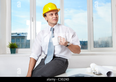 Portrait de l'architecte à boire du thé en fonction du casque Banque D'Images